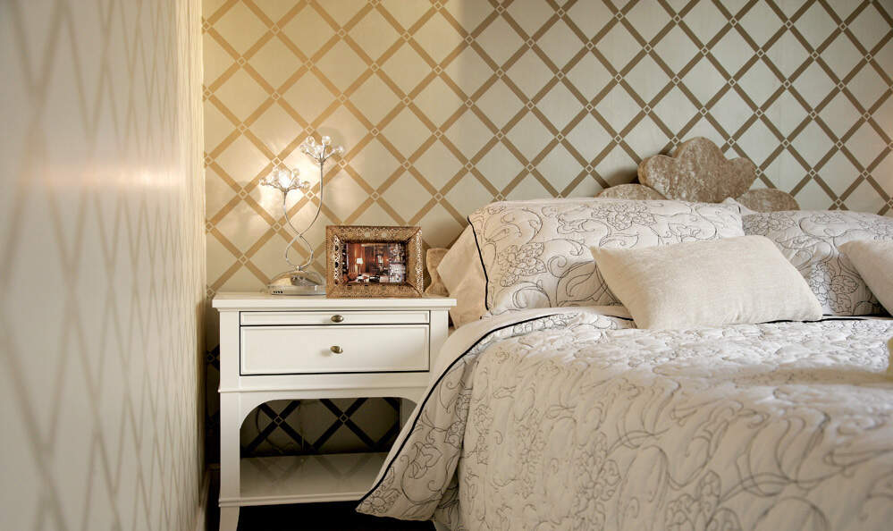 精致的白色床头柜搭配家纺的花纹，诠释新古典风格的讲究