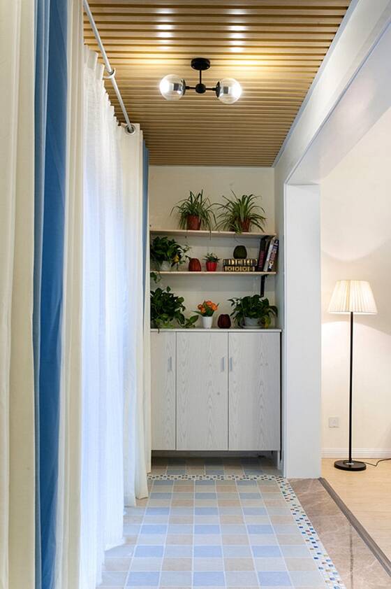 纱织的白色窗帘和蓝色窗帘不仅让客厅更加梦幻也突出了夏日的色彩。阳台的壁柜也增加了房间的储存能力。摆上几盆绿植，净化空气的同时也能装饰阳台。
