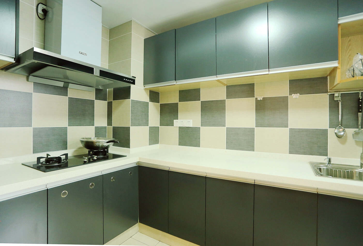 厨房的位置，采用的橱柜是一种黑色的一种颜色，台面还是现代风格比较流行的白色，四周墙壁都是用的壁纸相对来说是简约型厨房。