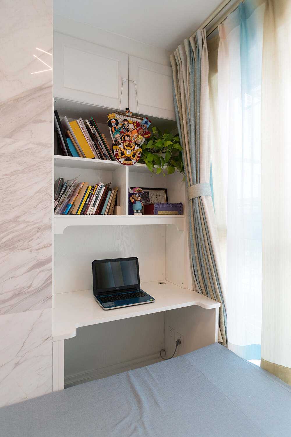 利用墙壁的小空间，安装了一个简单的白色木质电脑桌，桌子下方方便放腿，上面的柜子还能摆书和储存。