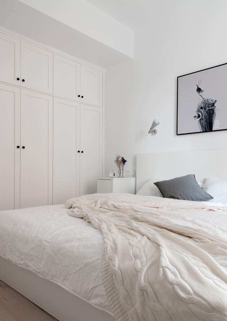 卧室以白色调为主，白色的衣柜，白色的杯子床单给人一种简单清新的氛围，墙上的插画，正好和白色互为补充，不至于颜色太单调。