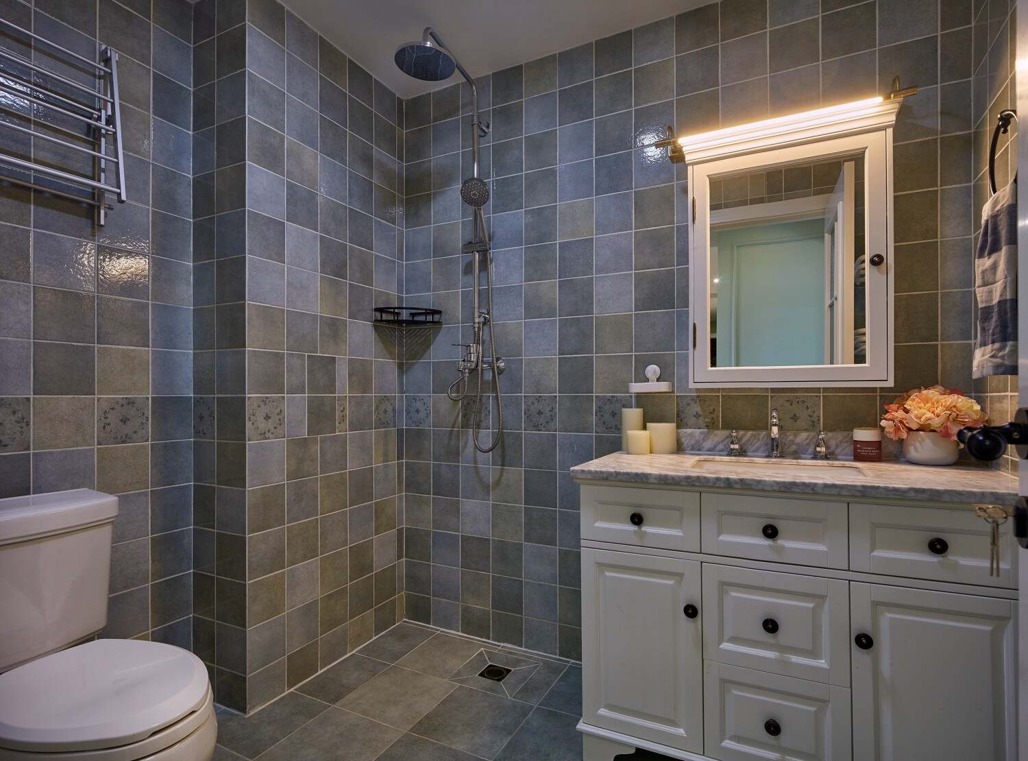 浴室还是保持的瓷砖的材料铺贴而成，那么浴室柜是采用美式主材的一种风格。浴室镜安装了灯饰，有一些装饰的效果。